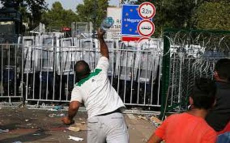 migrant throw bottle at Hungarian riot police at border