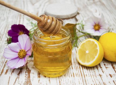 Jars of honey and lemons on wooden table