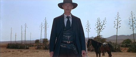 Col. Mortimer in For a Few Dollars More Both of Mortimer's belts - his trouser belt and his black gun belt - are seen as Manco directs the standoff against El Indio.