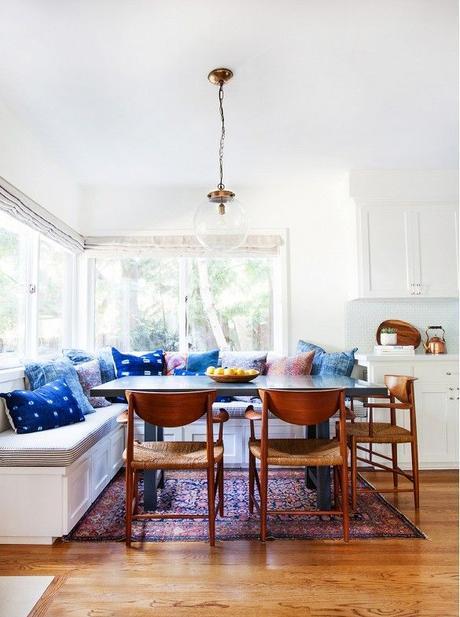 Breakfast nook with indigo Shibori dyed pillows and woven midcentury dining chairs.: 