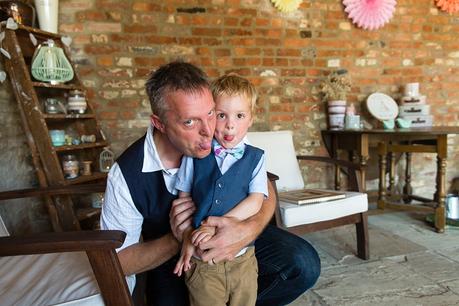 Canidid photographs at barmbyfiled barn wedding pageboy sticking tongue out