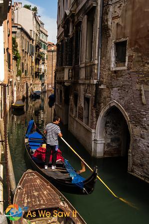 A gondolier makes his way home through a narrow canal.