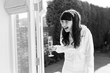 Bride laughs holding champagne Langar Hall Wedding Photography