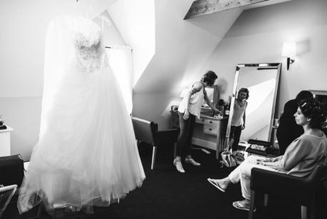 bride getting ready with dress nearby
