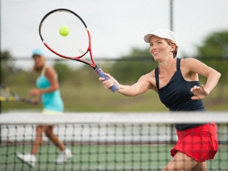 young woman playing Doubles tennis, hitting a forehand volley