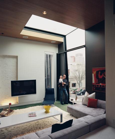In the living room, a double-height window and a skylight work together to frame a view of the Victorian Gothic church just across the street.