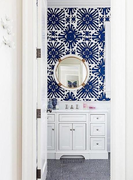 Obsessed with the bold cobalt blue and white geometric sunburst patterned wallpaper and shiny brass and chrome accents in this adorable bathroom.  Read more on our Style Guide, 