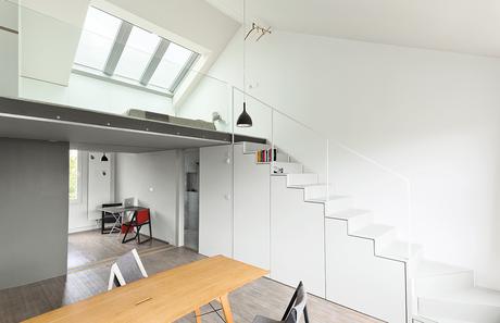 Modern white cabinets under the stairs with skylight above