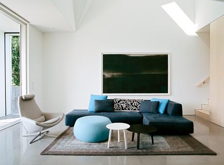 Concrete floor, white walls, Bend sectional sofa, Metropolitan chair by B&B Italia, and Arper pouf in living room of Rhode Island family vacation home by Bernheimer Architecture.