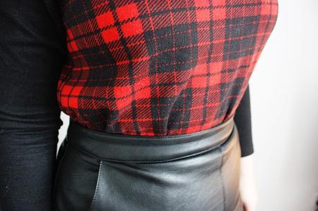 Close up of a line leather skirt and red tartan raglan jumper