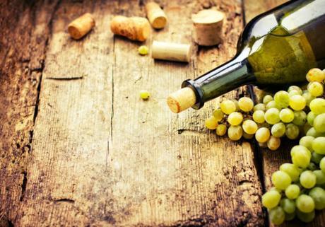 Bottle of wine, grape and corks on wooden table