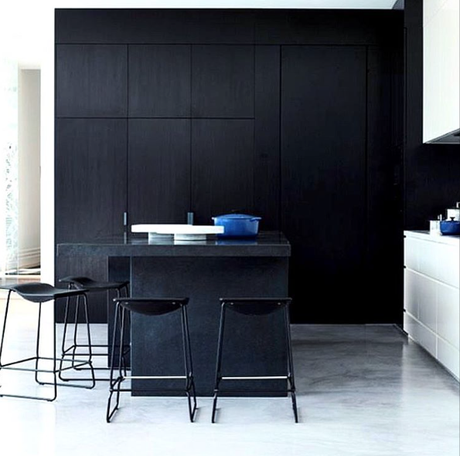 A kitchen with a wall of black cabinets