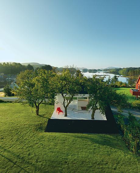 modern guesthouse in norway with angular facade and cutaway patio with spruce cladding and ikea chair