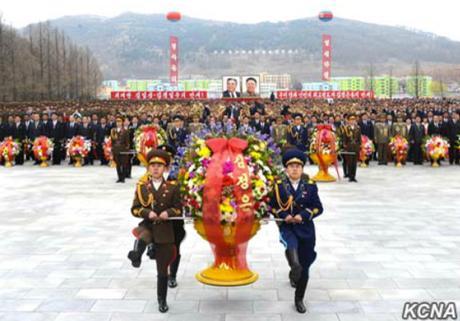 An honor guard representing the KPA's service branches carries a floral basket from Kim Jong Un to the foot of the statues on April 12, 2016 in So'ngch'o'n, South P'yo'ngan Province (Photo: KCNA).