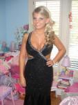 Fair skinned blonde high school student in a black and silver dress that has side cutouts and a deep neckline. that shows her cleavage