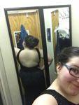 Selfie taken in a mirror to show the back of a black dress that is essentially backless.