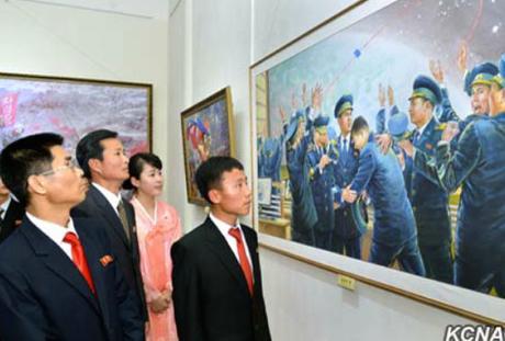 DPRK citizens look at a painting depicting National Aerospace Development Agency personnel celebrating a rocket launch (Photo: KCNA).
