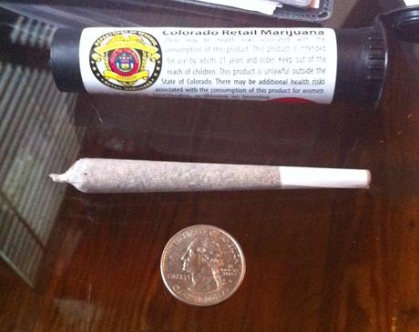 A pre-rolled joint next to a quarter