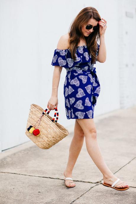 Amy Havins wears a blue off the shoulder dress with flat sandals.