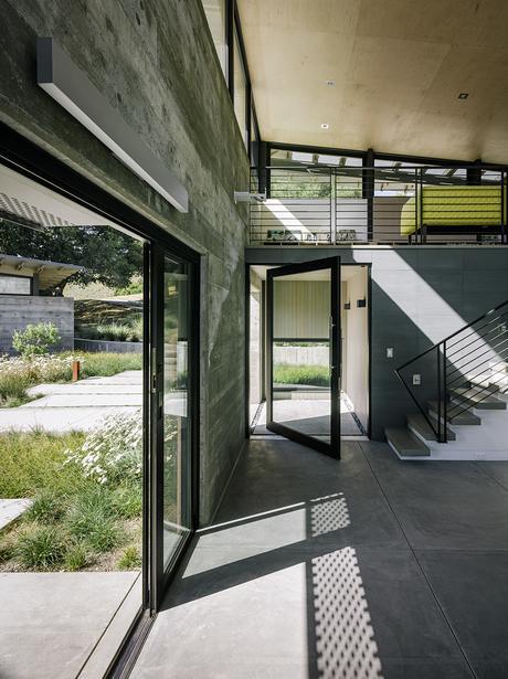 Entryway of modern eco-conscious pavilion in California by Feldman Architecture with Fleetwood glass windows, furnished with Ligne Roset sofa.