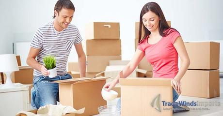 Happy young couple sitting on the floor of new flat and unpacking boxes