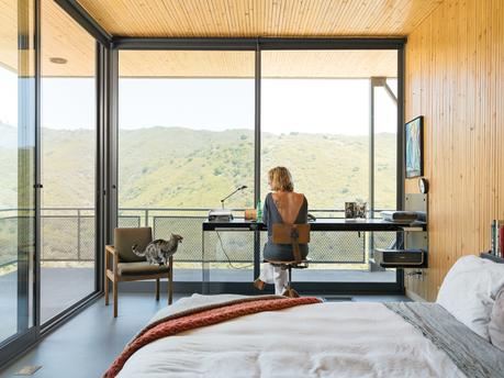 Modern bedroom office with floor-to-ceiling sliding glass doors 