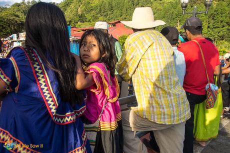 Little Embera girl with her mother looking over her shoulder at the rides she wants to enjoy