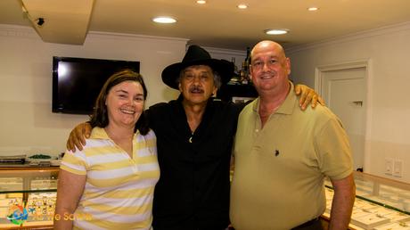 Owner of a silver jewelry shop happy to see a few tourists interested in fine silver necklaces. 