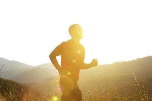Silhouette of a man running outdoors with sunsetting behind him