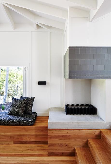 Modern timber house living area fireplace covered by charcoal tiles and a custom bench