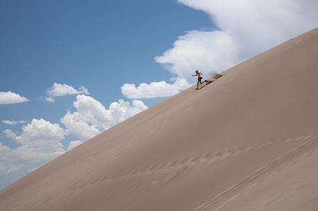 Visitor running down a dune in Great Sand Dune...