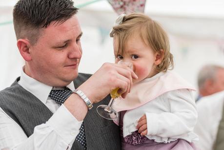 a little girl having a drink at a wedding 