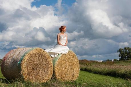 bride sitting on hay bails at a rustic wedding 