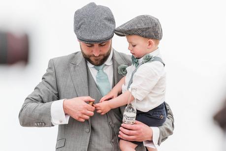 an usher holding his son at a summer wedding 