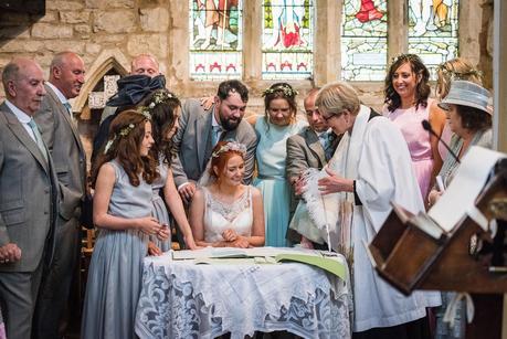 bridal party watching the bride sign the register