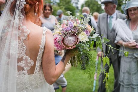 a bride holding her flowers outside the church 