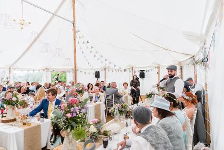 A groom speaking to a room full of wedding guests