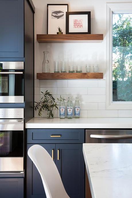 Blue Cabinetry And White Quartz Countertop And Floating Wood Shelves