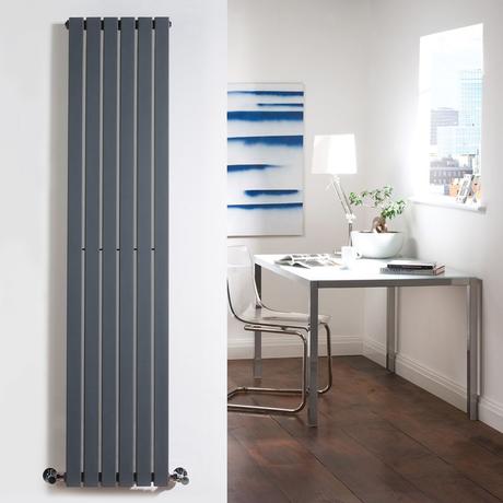 Vertical designer radiator on a wall with a chair and desk in the background