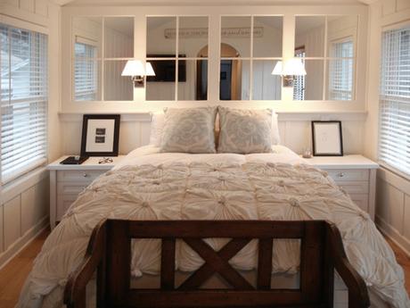 Small bedroom with mirrors to make it look bigger behind the bed on the wall