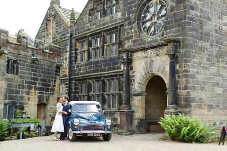 Bride & Groom pose for kisses next to Morris Minor in front of East Riddelsden Hallat Wedding 