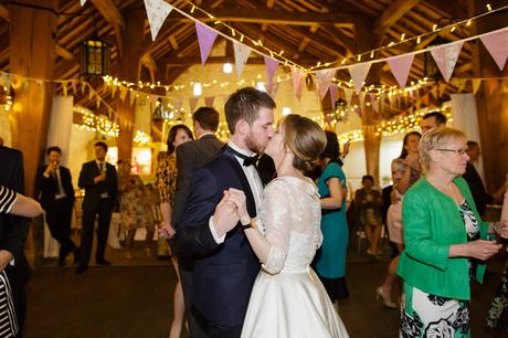 Bride & groom kiss during dance at East Riddlesden Hall with Bunting