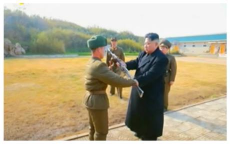 Kim Jong Un presents an automatic rifle to a service member of the Changjae Islet coastal defense detachment. Behind Jong Un are a member of the Guard Command and the head of close security escort detail (Photo: Korean Central Television).