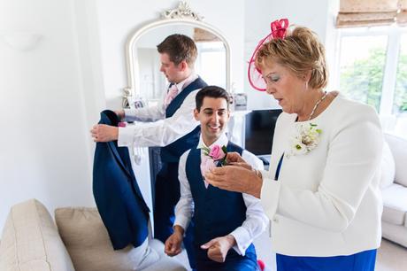 Groom & best man being helped with their buttonholes by groom's mum