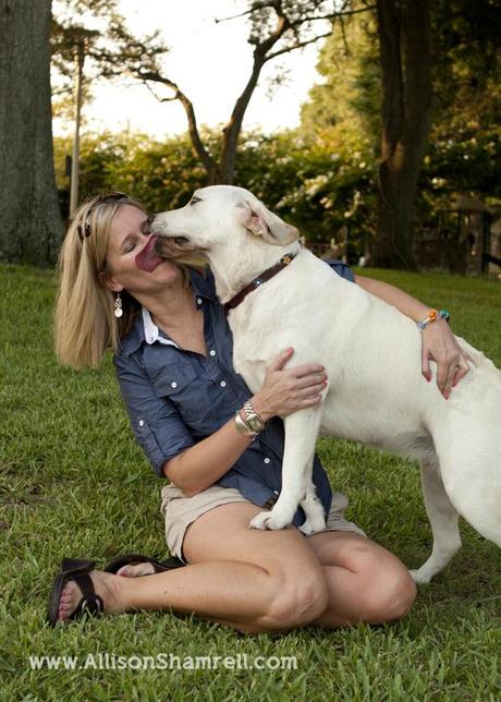 A labrador kisses his mom as they sit in a park.