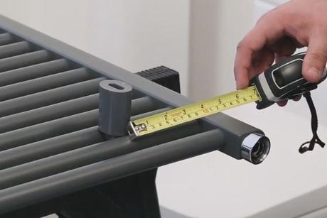 man measuring the distance between the center of a bracket and the edge of a heated towel rail