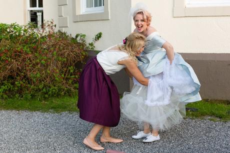 Bridesmaid helps bride adjust petticoat 