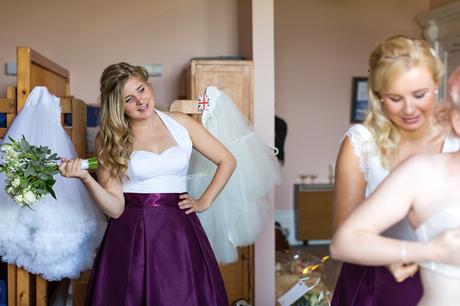 Bridesmaid watches on as bride gets dressed 