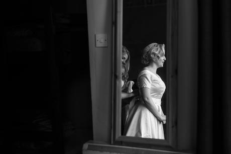 Reflection of bride being buttoned up in mirror Derwentwater Independent Hostel Wedding