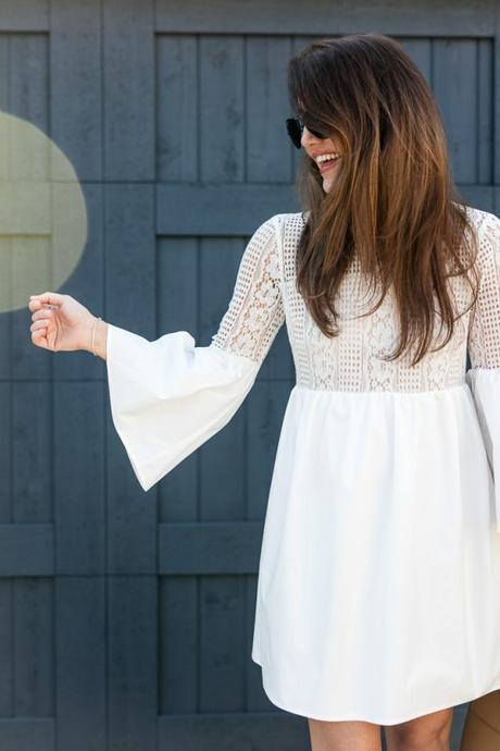 Amy Havins wears a white bell sleeve mini lace dress with stuart weitzman heels.
